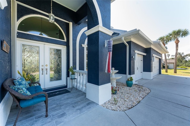 entrance to property featuring an attached garage, stucco siding, and french doors