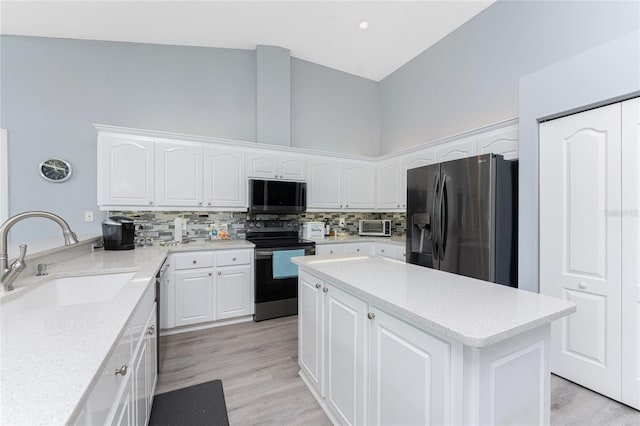 kitchen featuring white cabinets, light stone counters, appliances with stainless steel finishes, a sink, and backsplash