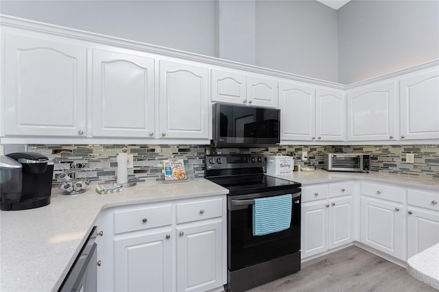 kitchen with appliances with stainless steel finishes, white cabinetry, light wood-style floors, and tasteful backsplash