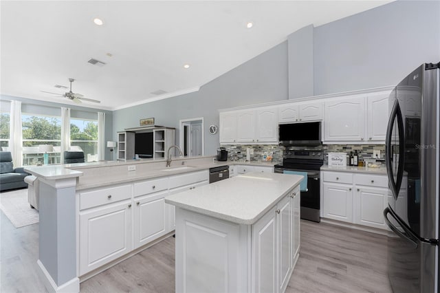 kitchen featuring a peninsula, a kitchen island, open floor plan, freestanding refrigerator, and stainless steel electric stove