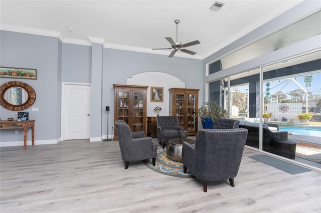 living room with light wood finished floors, a ceiling fan, visible vents, and crown molding