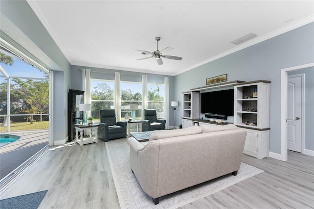 living room featuring a healthy amount of sunlight, light wood-style flooring, and crown molding