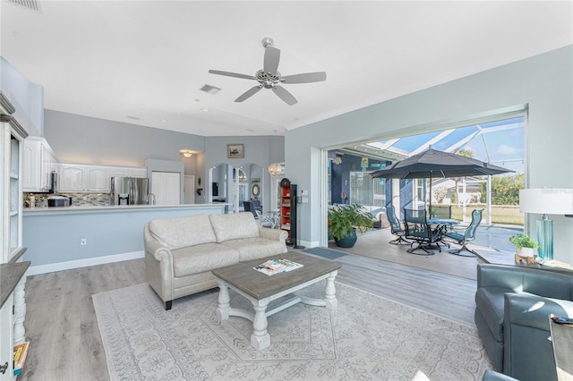 living area featuring a sunroom, light wood-style flooring, arched walkways, and ceiling fan