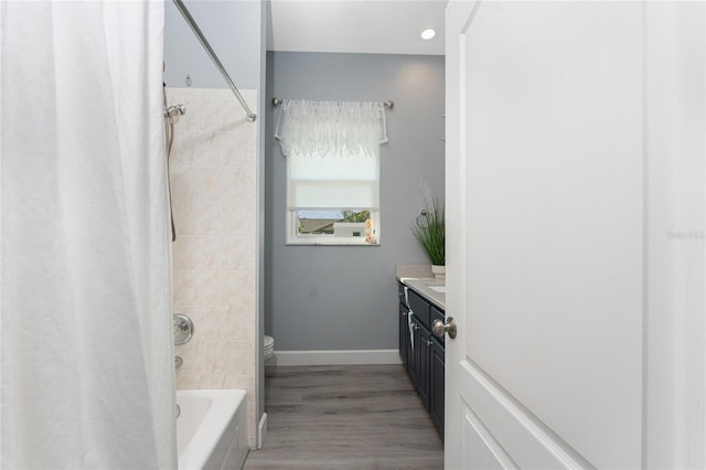 full bath with baseboards, toilet, wood finished floors, shower / bath combination with curtain, and vanity