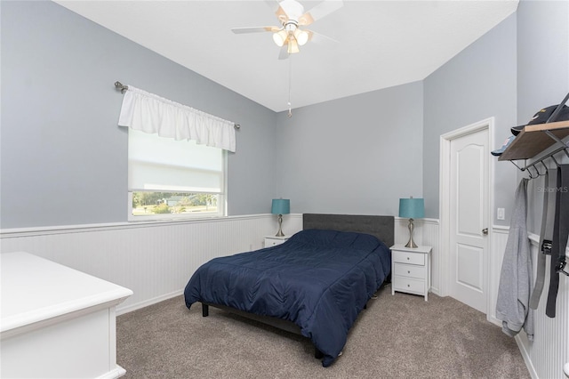 carpeted bedroom featuring lofted ceiling, a ceiling fan, and wainscoting