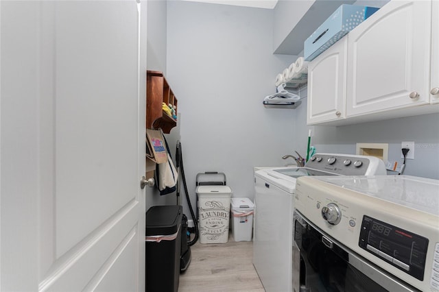 laundry area featuring light wood-type flooring, cabinet space, and washer and dryer