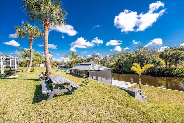 dock area with glass enclosure, a lawn, and a water view