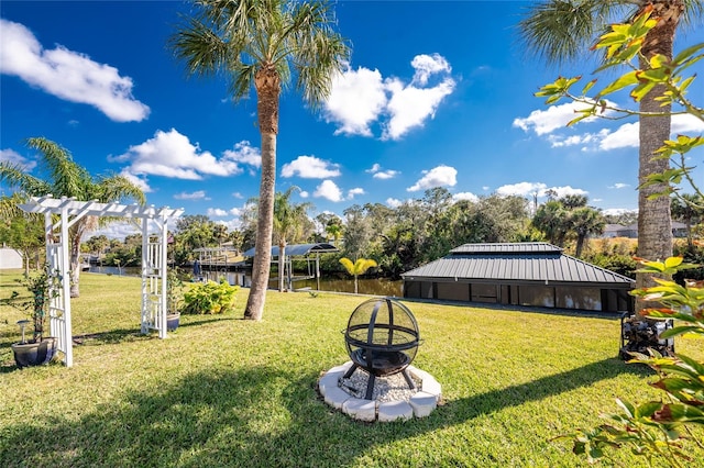 view of yard with a water view, an outdoor fire pit, and a pergola