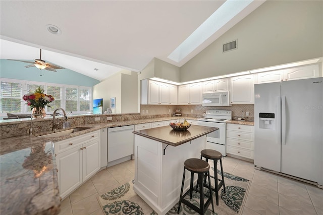 kitchen with white appliances, a skylight, sink, and white cabinets