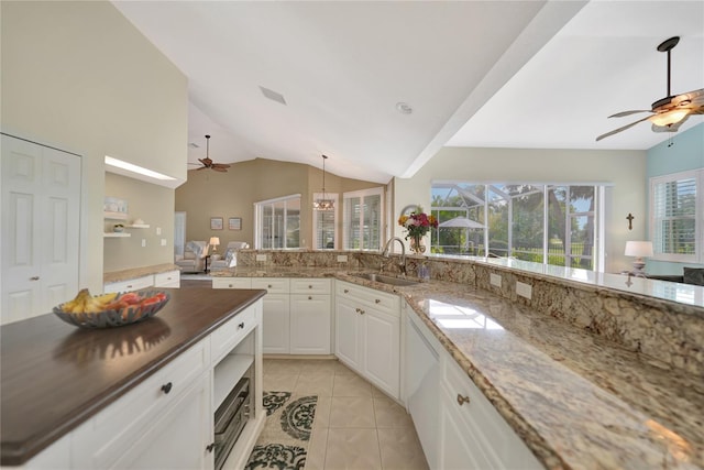 kitchen with sink, light tile patterned floors, ceiling fan, dark stone counters, and white cabinets