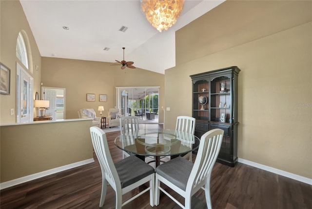 dining room with dark wood-type flooring, ceiling fan with notable chandelier, and high vaulted ceiling