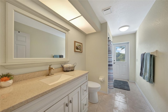 bathroom featuring vanity, toilet, tile patterned flooring, and a textured ceiling