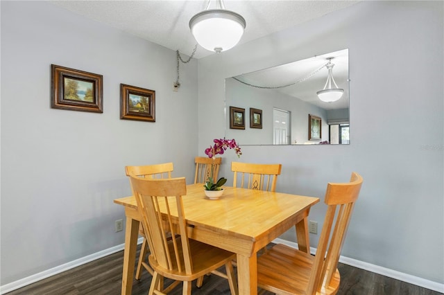 dining room with dark wood-type flooring and a textured ceiling