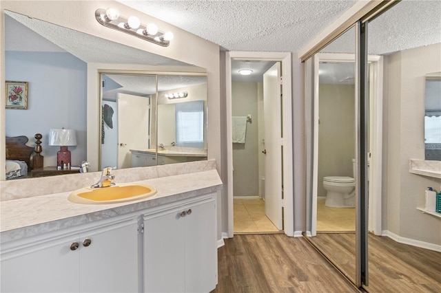 bathroom with wood-type flooring, toilet, a textured ceiling, and vanity