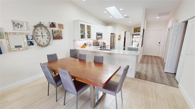 dining area featuring lofted ceiling with skylight and sink