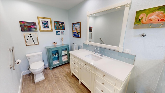 bathroom with tasteful backsplash, wood-type flooring, toilet, and vanity