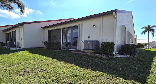 back of house with central AC unit and a lawn