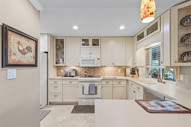 kitchen with sink, white appliances, cream cabinets, decorative backsplash, and decorative light fixtures