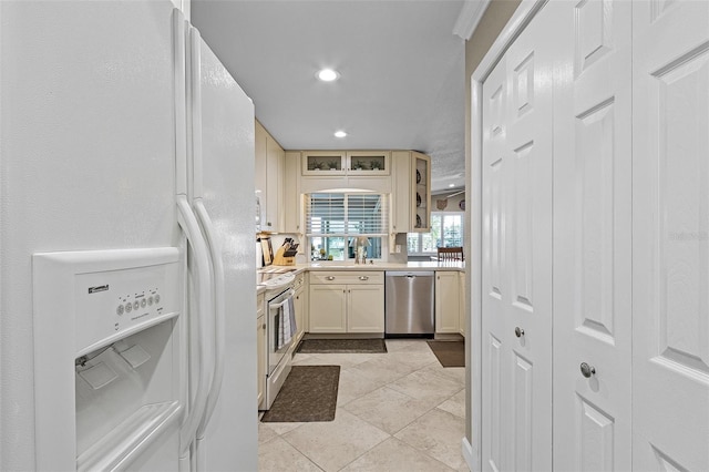 kitchen featuring cream cabinets, sink, light tile patterned floors, and white appliances