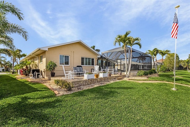 rear view of property featuring a patio, glass enclosure, and a lawn