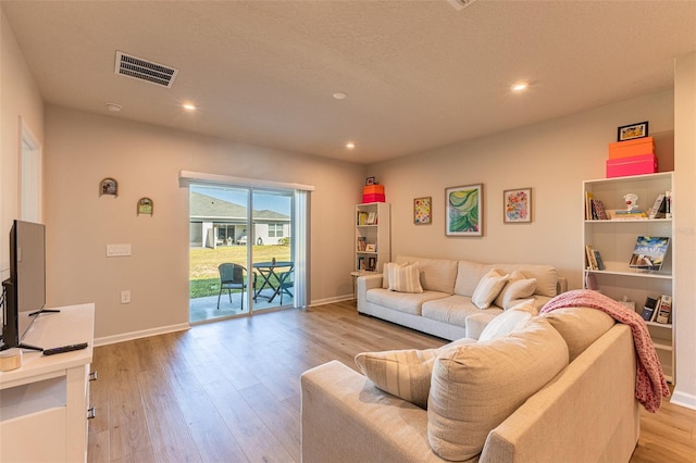 living room with a textured ceiling and light wood-type flooring