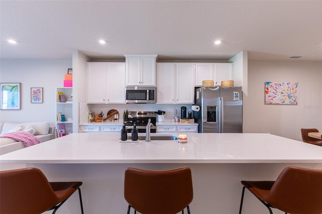 kitchen with stainless steel appliances, white cabinetry, a large island, and a kitchen breakfast bar