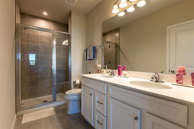 bathroom featuring vanity, toilet, a shower with shower door, and tile patterned flooring