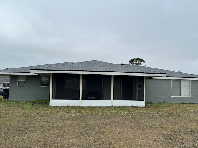 back of house featuring a sunroom, a lawn, and roof with shingles