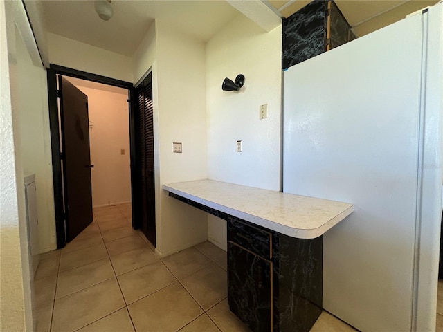 kitchen with a peninsula, light tile patterned floors, light countertops, and freestanding refrigerator