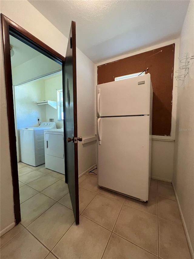 kitchen featuring freestanding refrigerator, light tile patterned flooring, baseboards, and separate washer and dryer