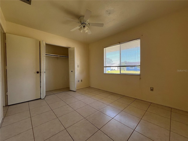 unfurnished bedroom with light tile patterned floors, ceiling fan, and a closet