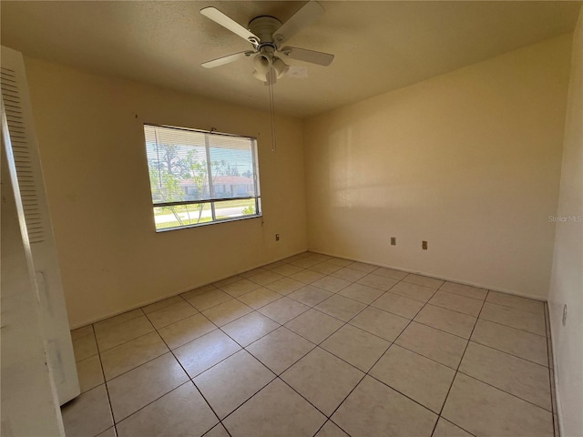 empty room with a ceiling fan and light tile patterned flooring