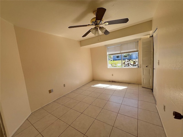 empty room with light tile patterned floors and a ceiling fan