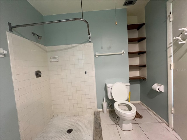 bathroom featuring visible vents, toilet, tiled shower, baseboards, and tile patterned floors