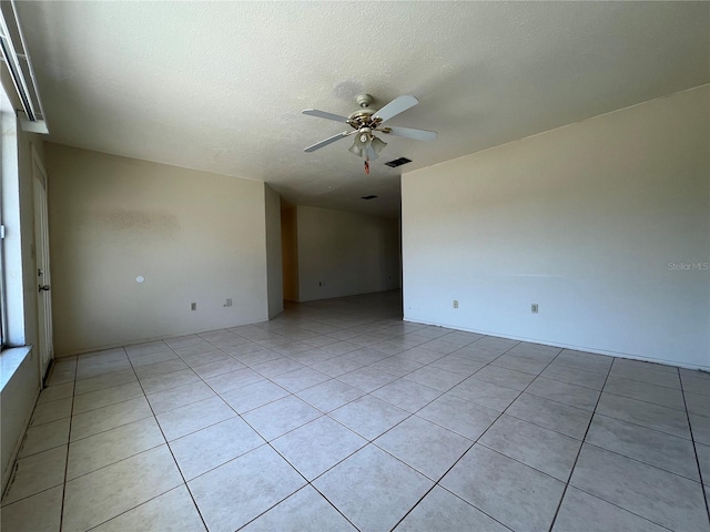 spare room featuring a textured ceiling, visible vents, a ceiling fan, and light tile patterned flooring