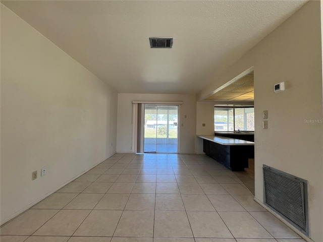 spare room featuring visible vents, a textured ceiling, and light tile patterned floors