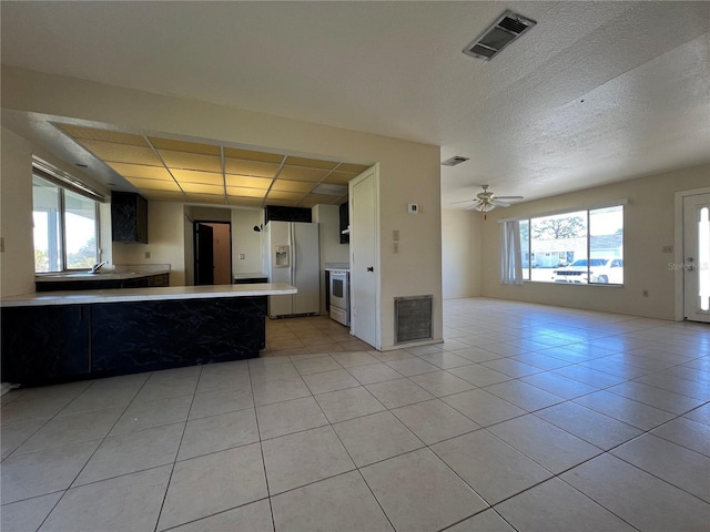 kitchen featuring light countertops, white refrigerator with ice dispenser, visible vents, and open floor plan