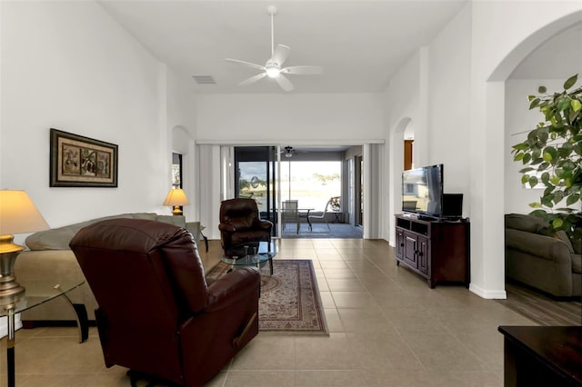 living room with light tile patterned flooring, ceiling fan, and a towering ceiling