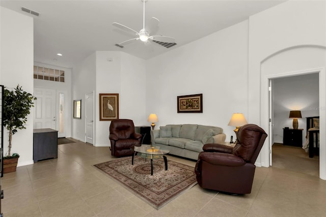 living room featuring a towering ceiling, light tile patterned floors, and ceiling fan