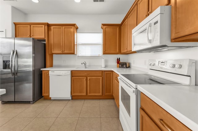 kitchen featuring sink, light tile patterned floors, and white appliances