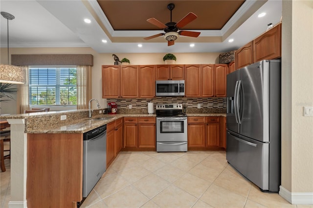 kitchen with a raised ceiling, appliances with stainless steel finishes, hanging light fixtures, and kitchen peninsula