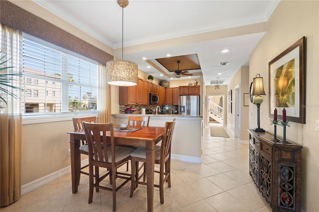 tiled dining space featuring sink, a tray ceiling, ornamental molding, and ceiling fan