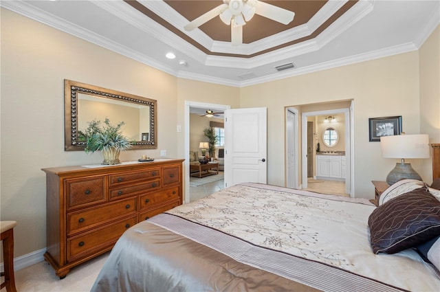 carpeted bedroom with crown molding, connected bathroom, a tray ceiling, and ceiling fan