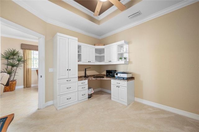 carpeted office space featuring ceiling fan, ornamental molding, a tray ceiling, and built in desk