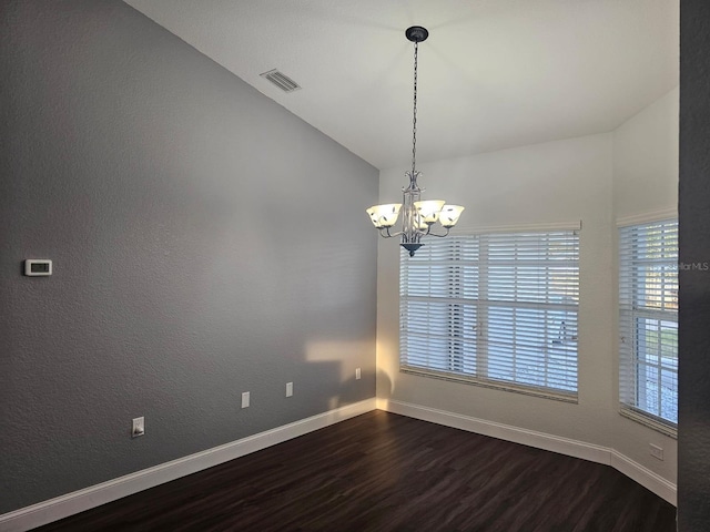 spare room with dark hardwood / wood-style flooring, vaulted ceiling, and a notable chandelier