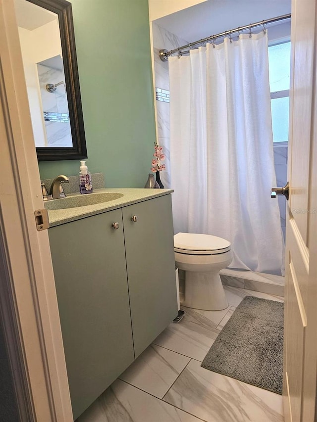 bathroom featuring vanity, walk in shower, and toilet