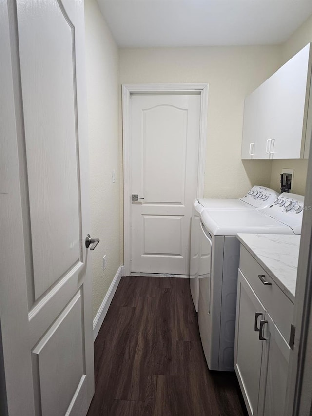 clothes washing area featuring cabinets, dark hardwood / wood-style floors, and washer and clothes dryer