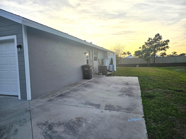 property exterior at dusk featuring central AC and a yard