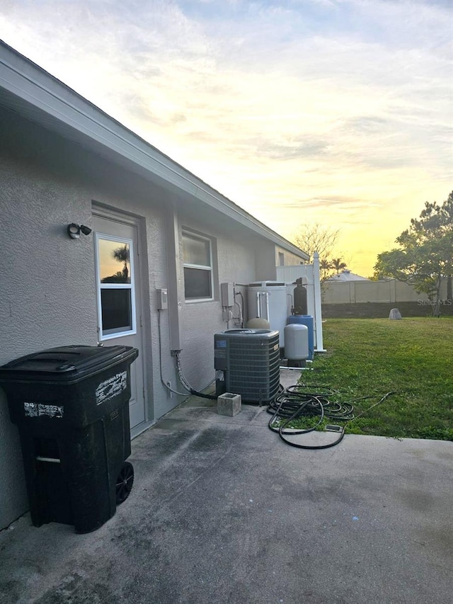 patio terrace at dusk with a lawn and central air condition unit