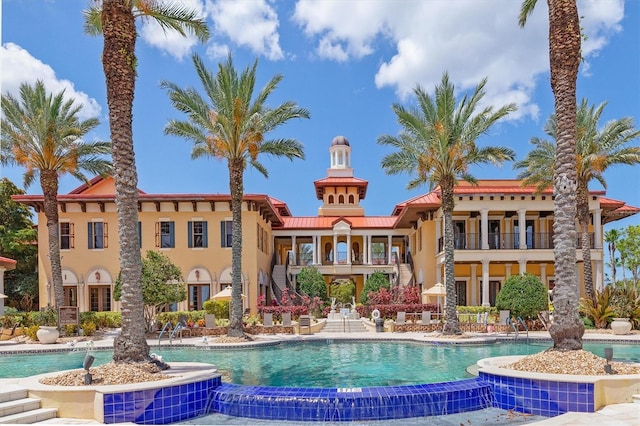 rear view of house featuring a balcony and a community pool